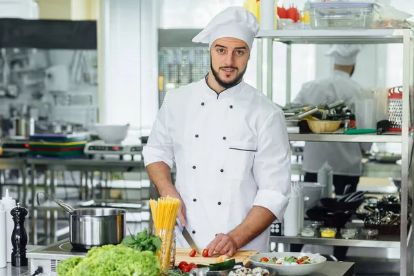 ナイフ野菜でシェフの料理 若い髭を生やした男が職場で食事のコンセプト — ストック写真