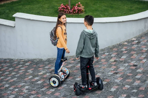 孩子们迷人的伴侣们在街上骑电动车 享受着夏日的快乐 — 图库照片