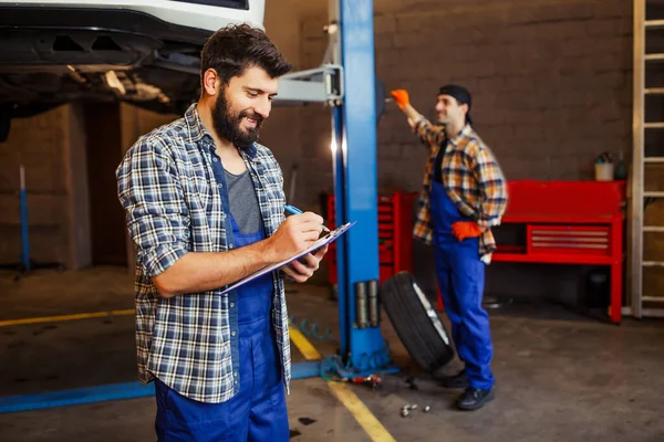 Δύο Automechanics Που Εργάζονται Ανυψωμένο Αυτοκίνητο Στο Εργαστήριο Ένα Αυτοκίνητο — Φωτογραφία Αρχείου