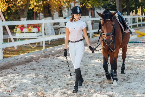 若いです女性で特別な制服とヘルメットとともに彼女の乗馬馬 — ストック写真