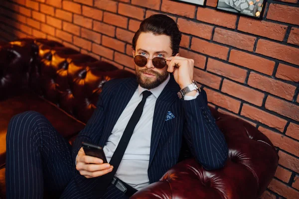 Atraktivní Módní Muž Obleku Sedí Kožené Pohovce Drží Smartphone Komfort — Stock fotografie