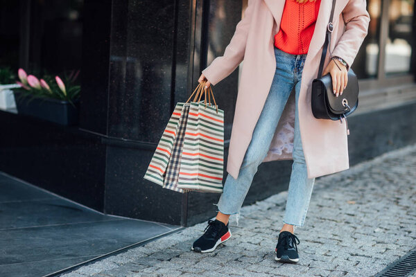 Фото крупным планом. Взгляд на улицу, одежда. Женщина с пакетами покупок. Модная девушка остается возле бутика
.