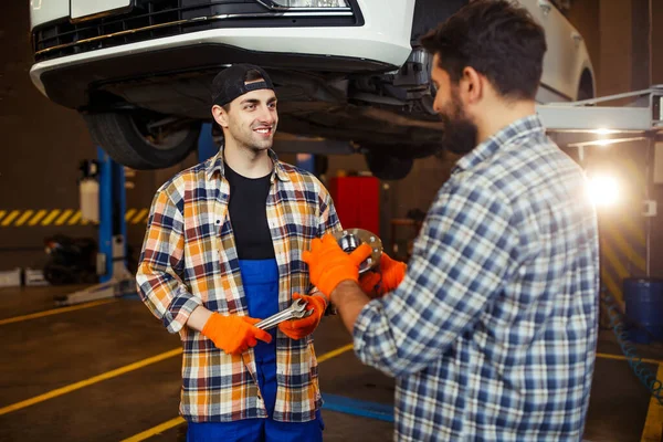 Uśmiechnięci Specjaliści Trzymający Detale Samochodu Kluczy Rozmawiający Razem Garażu Efekt — Zdjęcie stockowe
