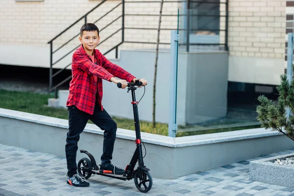 穿着红色衬衫的可爱小男孩骑摩托车 快乐的少年骑着现代的摩托车 — 图库照片