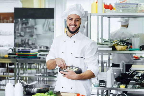 Portrait of the smiling chef in the kitchen of the restaurant with a ready madeeggs,  dish on his hands.