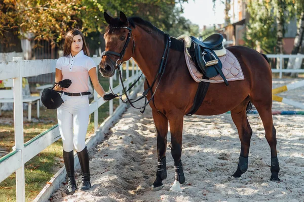 特別な制服を着た若い女性と彼女の乗馬馬とヘルメット 馬術スポーツの馬場馬術 — ストック写真