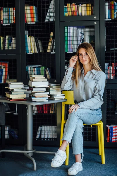 Güzel Sarışın Kadın Manken Üniversite Kütüphanesinde Masada Kitaplarla Oturuyor — Stok fotoğraf