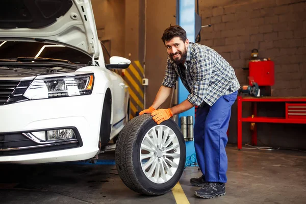 Pełne Ujęcie Młodego Mechanika Zmieniającego Oponę Patrzącego Kamerę Garażu — Zdjęcie stockowe