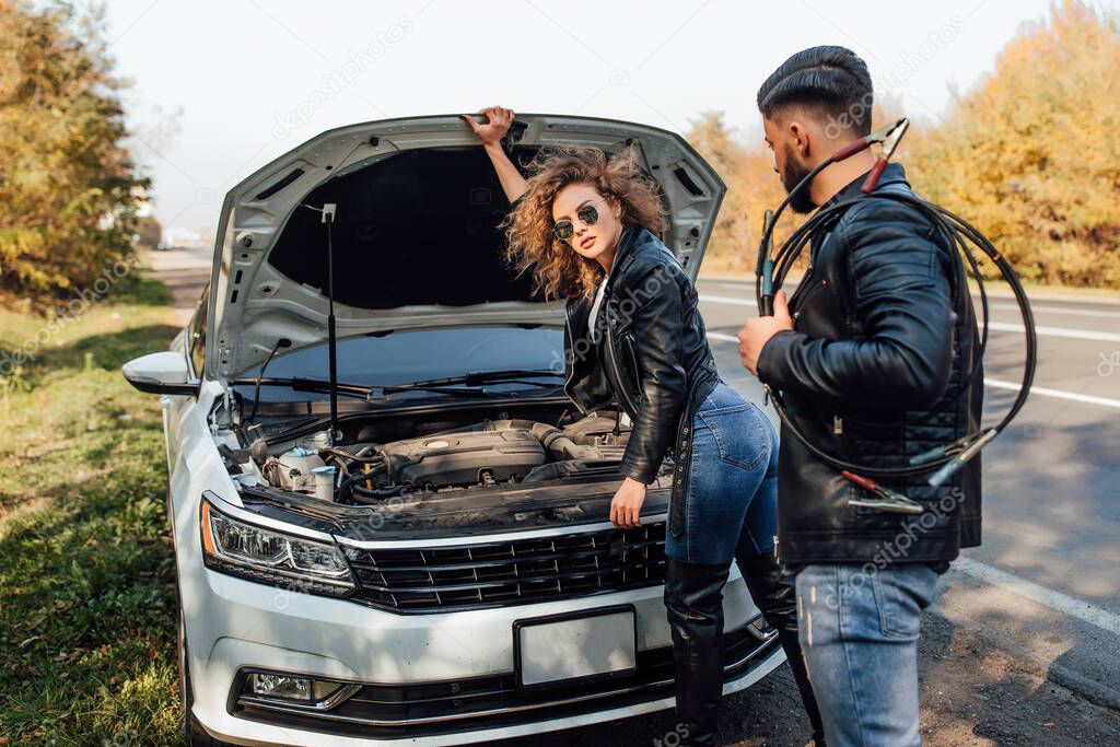 The young woman broke down the car while traveling on the way to rest, bearded strong man help her on road.