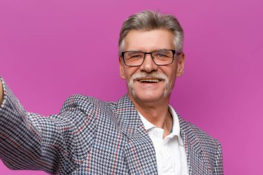 Gözlüklü mutlu son sınıf öğrencisinin portresi. Mor arka planda poz verirken gülümsüyor. Selfie zamanı..