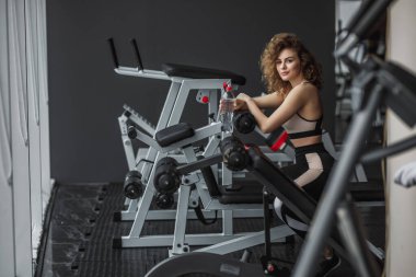 Sportif genç sarışın sporcu antrenmandan sonra dinleniyor ve spor salonunda suyla şişeyi tutuyor..