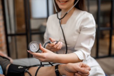 Kesilmiş görüntü. Kadın doktor ve hemşire yatağında yatan yaşlı hastaya kan basıncını ölçüyorlar..