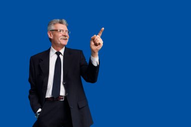 Mutlu kıdemli iş adamları mavi arka planda kalırken fotokopi alanını gösteriyorlar..