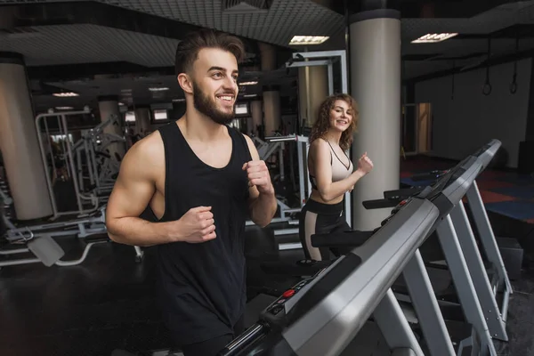 Running time, portrait of young sports couple making cardio workout in modern gym.