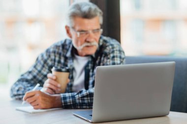 Laptopa odaklan, yaşlı adam kafede bilgisayar başında çalışıyor kahve içiyor, yaşam tarzı kavramı..
