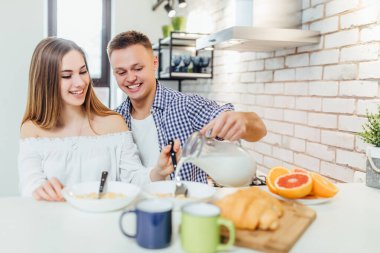 Beyaz ev mutfağında birlikte sağlıklı yemek pişiren gülümseyen genç çift. ..