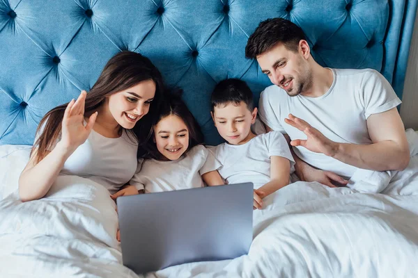 快乐的家人在家里用笔记本电脑躺在床上 与父母交谈 — 图库照片