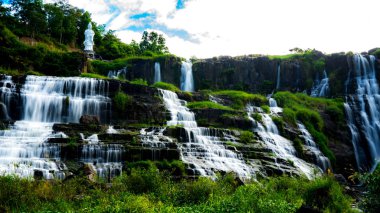 Vietnam 'daki inanılmaz Pongour şelalesi, tepesinde Buda' yla Da Lat. Seyahat konsepti, yağmur ormanlarına düşen kristal berrak su manzarası. Güzel doğa duvarcısı..