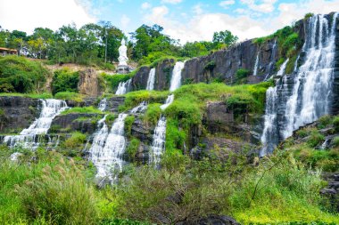 Vietnam 'daki inanılmaz Pongour şelalesi, tepesinde Buda' yla Da Lat. Seyahat konsepti, yağmur ormanlarına düşen kristal berrak su manzarası. Güzel doğa duvarcısı..