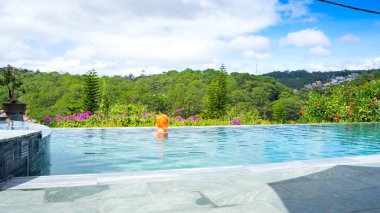 Havuzdaki genç bir kız Dalat şehrinin dağlık kesimlerinde güzel bir manzaraya hayran..