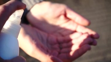 Adam virüsten korunmak için kadın ellerine dezenfektan sıkar. Corona virüsü kovid-19 'u önlemek için alkol jeli sanitazer sıvısı temizler. Sokakta el dezenfektanı ile korunur..