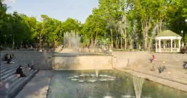 Ukrayna 'nın başkenti Kharkov' da 13 Mayıs 2020 'de, halka açık yüksek çeşmenin karantina sonrası yaz mevsiminde güneşli parka su püskürtmesi, insanların parkta yürüyüp dinlenmesi ve dinlenmesi