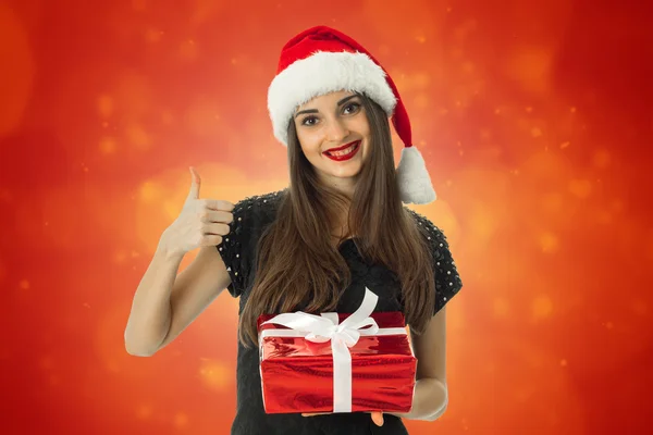 Girl smiling in santa hat with red gift — Stock Photo, Image