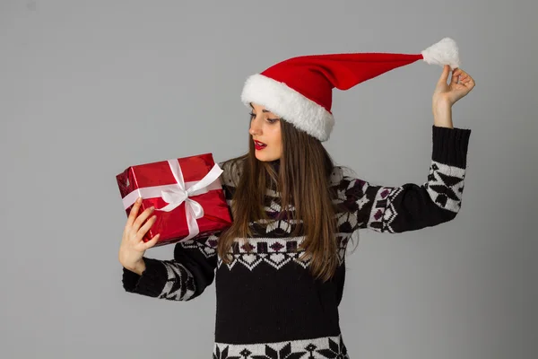 Mulher em camisola quente e chapéu de santa com presente vermelho — Fotografia de Stock