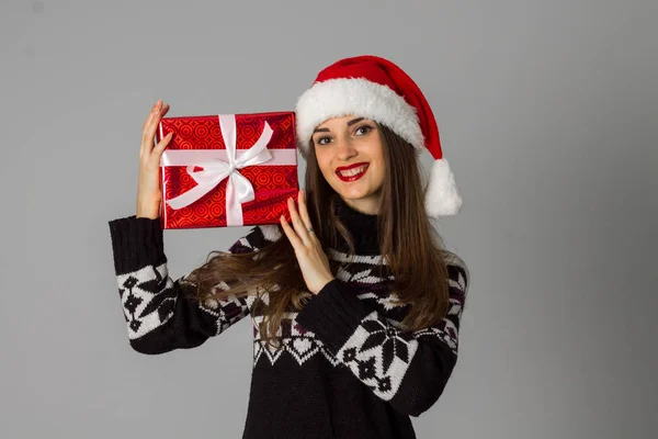 Жінка в теплому светрі і капелюсі Санта з червоним подарунком — стокове фото