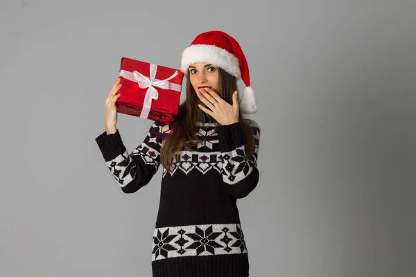Жінка в теплому светрі і капелюсі Санта з червоним подарунком — стокове фото