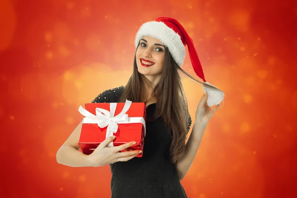 Giovane donna in cappello di Babbo Natale con regalo rosso — Foto Stock
