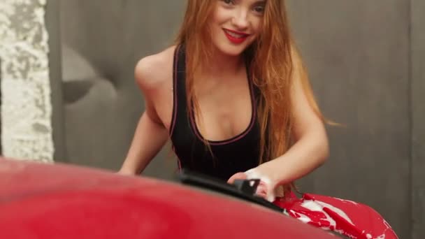 Jeune femme aux lèvres rouges lave une voiture — Video