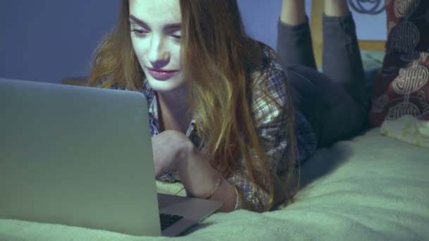 Chica acostada en la cama con el ordenador portátil — Vídeos de Stock