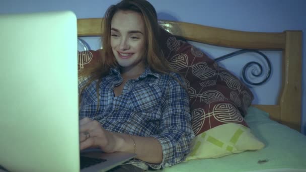 Dolce ragazza si trova con un computer portatile sul letto — Video Stock