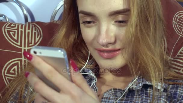 Девушка слушает музыку с наушниками по телефону — стоковое видео
