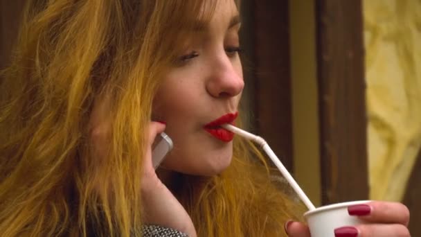 Το κορίτσι πίνει καφέ και μιλάει στο τηλέφωνο — Αρχείο Βίντεο