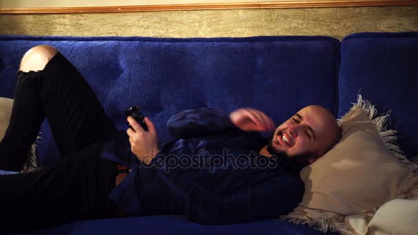 ソファと演劇のコンピュータ ゲームに横たわっている男 — ストック動画