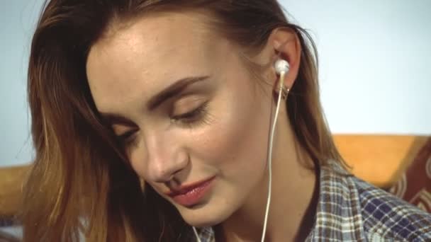Chica sonríe y escucha música con auriculares — Vídeo de stock