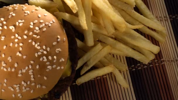 Gebakken aardappelen en een grote hamburger op tafel — Stockvideo