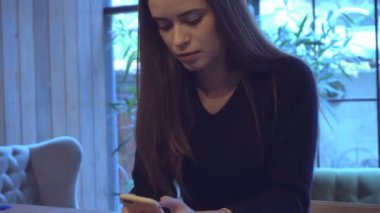 bir sandalyede oturuyor ve seyir telefon genç kız