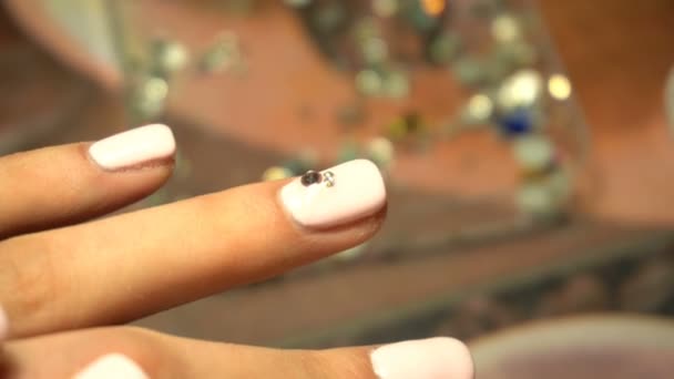 Maniküre legt die kleinen Kieselsteine zur Dekoration auf den Nagel — Stockvideo