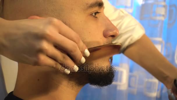 Girl evenly cuts and combing the beard the young guy close-up — Stock Video