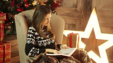 Kız oturur ve bir Noel odada bir kitap okuma