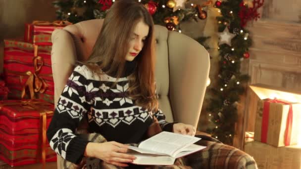 lány ül egy széken, és Olvasson egy könyvet a karácsonyi szoba