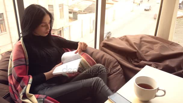 Menina bonita está bebendo chá e lendo um livro — Vídeo de Stock