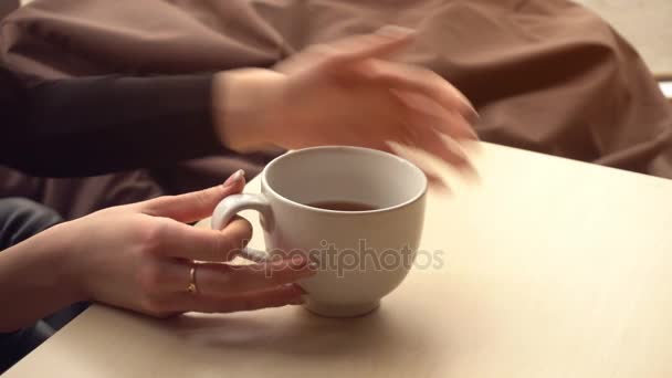 Girl takes a cup of tea on the table drinking and puts — Stock Video