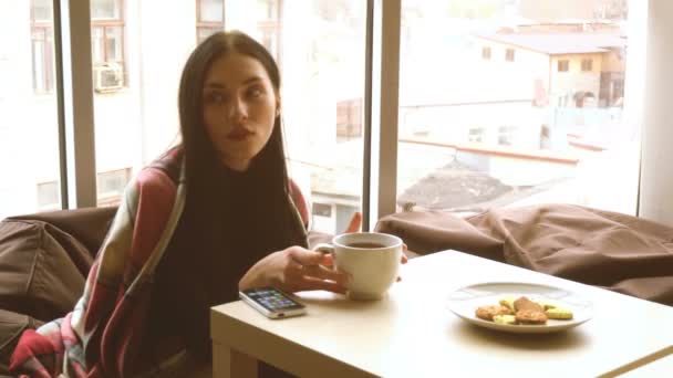 Genç kız bir sandalye ve bir fincan çay içme oturur — Stok video