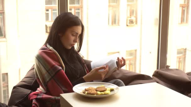 Krásná bruneta sedí a čte knihu — Stock video