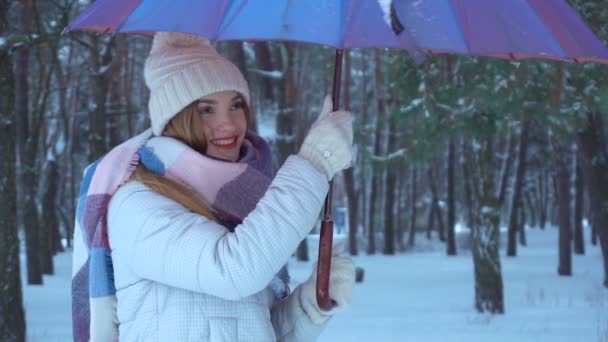 Девушка стоит под зонтиком и крутит его, и льет вокруг снега — стоковое видео