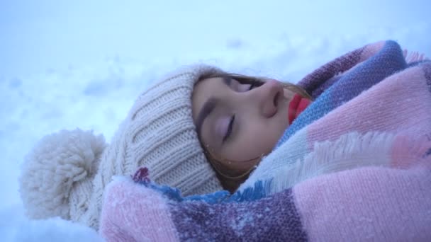 Belle fille aux lèvres rouges repose sur la neige et sourit — Video